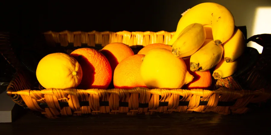 Cesta de frutas iluminada — laranjas e bananas em cesto de vime